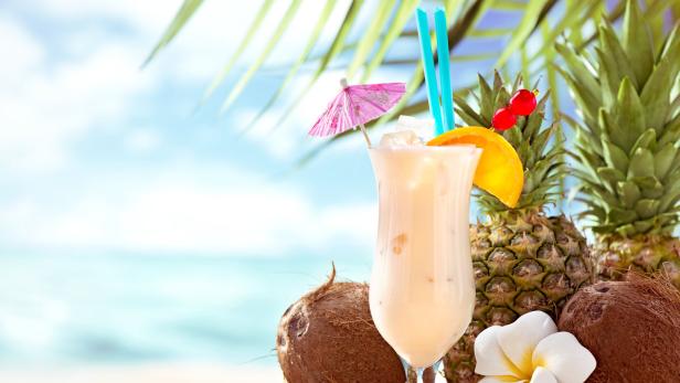 Ein Piña Colada Cocktail mit Ananas und Kokosnüssen am Strand.