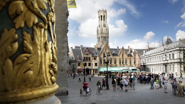 Der Marktplatz von Brügge mit dem Belfried im Hintergrund und vielen Menschen.