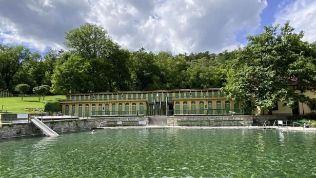 Ein Schwimmbad mit Umkleidekabinen und einer Rutsche an einem sonnigen Tag.