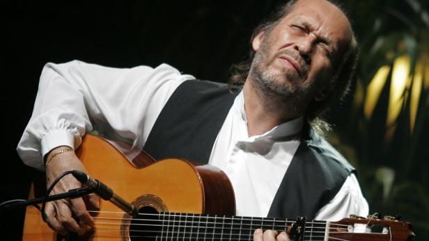 Ein Mann mit geschlossenen Augen spielt auf einer klassischen Gitarre.