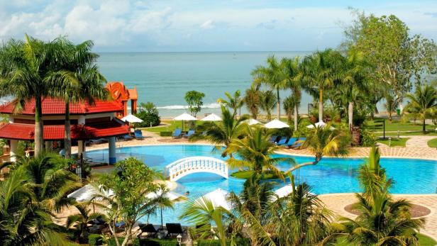 Ein Resort mit einem großen Pool, Palmen und Blick auf das Meer.