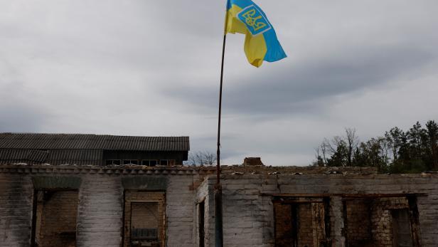 A Ukrainian flag is seen outside a destroyed house, as villagers return to Moshchun village