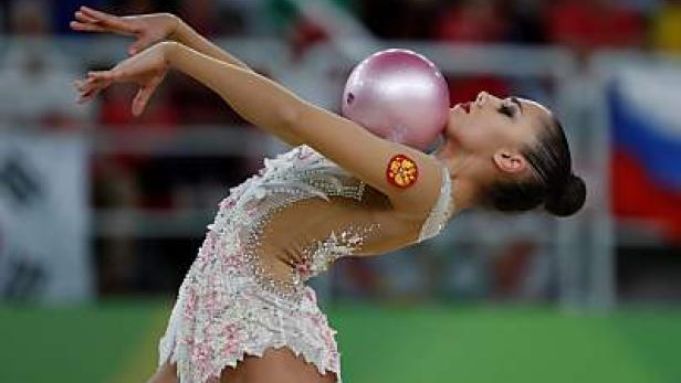 Eine rhythmische Sportgymnastin balanciert einen Ball auf ihrem Hals.