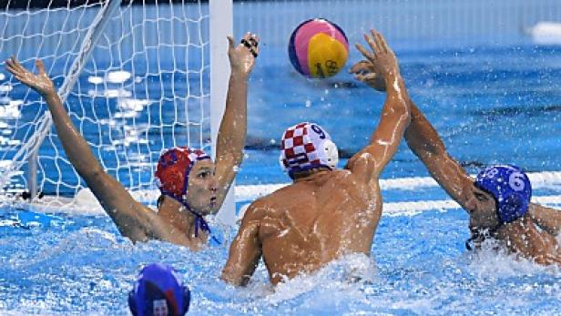 Wasserballspieler kämpfen um den Ball vor dem Tor.