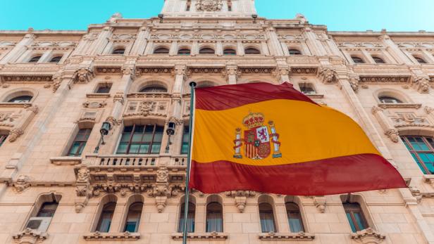 Die spanische Flagge weht vor einem verzierten Gebäude.