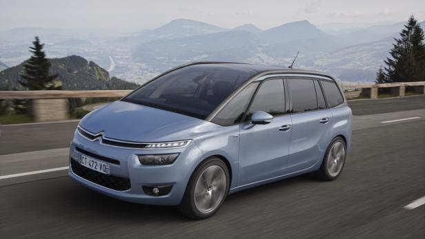 Ein blauer Citroën C4 Picasso fährt auf einer Straße mit Bergen im Hintergrund.