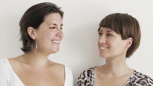 Zwei Frauen stehen lächelnd einander gegenüber.