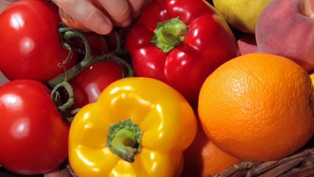 Eine Nahaufnahme von Tomaten, Paprika, einer Orange, einem Pfirsich und einer Birne.