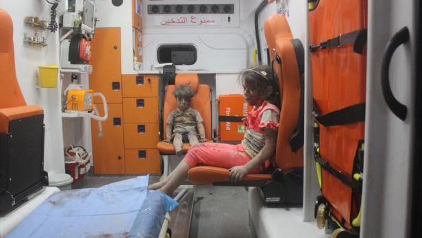 Omran sitzt mit seiner Schwester (rechts) in einem Krankenwagen.