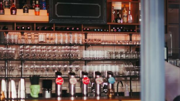 Eine Bar mit Hockern, Zapfhähnen und einer Tafel mit einem großen „B“.