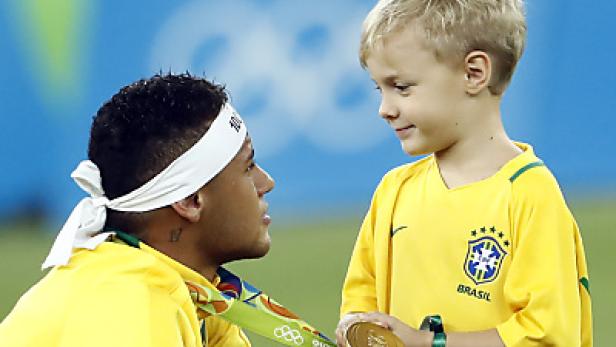Neymar mit Goldmedaille blickt auf einen kleinen Jungen im brasilianischen Trikot.