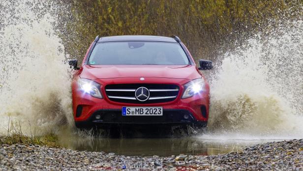 Ein roter Mercedes-Benz fährt durch eine Wasserpfütze.