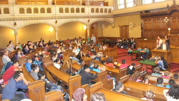 Eine Gruppe von Schülern sitzt in einem Gerichtssaal und hört aufmerksam zu.