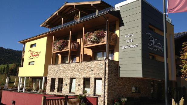Das Hotel „Mein Neubergerhof“ mit Balkonen und Blumenkästen an einem sonnigen Tag.