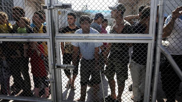 Eine Gruppe von Menschen steht hinter einem Metallzaun.