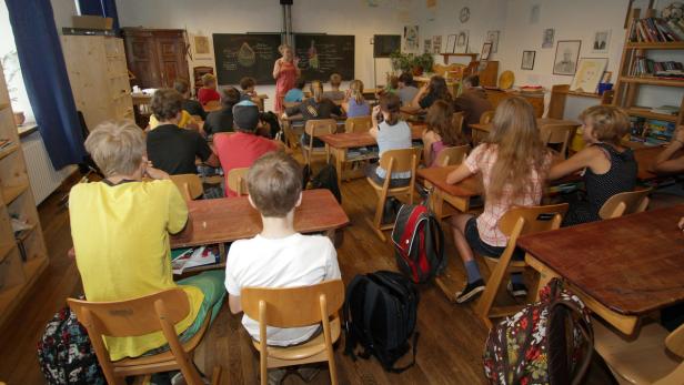 Eine Lehrerin erklärt den Schülern etwas an der Tafel in einem Klassenzimmer.