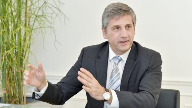 Ein Mann im Anzug gestikuliert an einem Tisch.