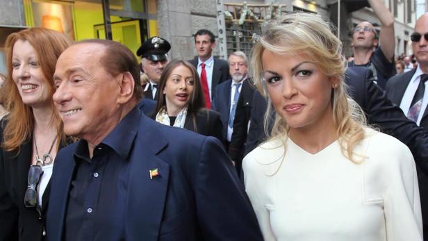 Silvio Berlusconi mit Begleitung bei einem öffentlichen Auftritt.