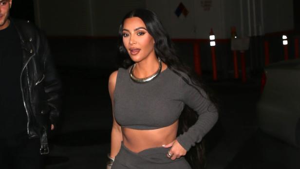 Kim Kardashian trägt ein graues zweiteiliges Outfit und Schnürschuhe.