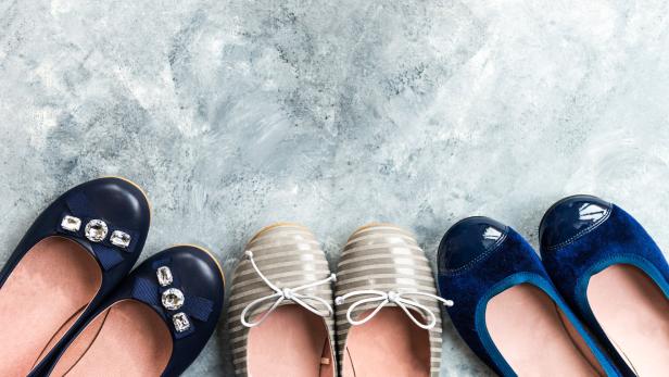 Mehrere Paar Ballerinas stehen auf einem grauen Hintergrund.