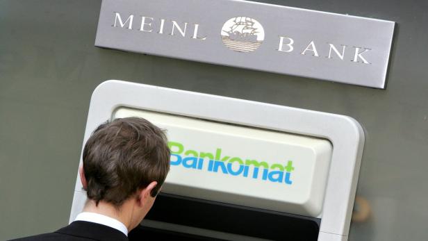 Ein Mann steht vor einem Bankomaten der Meinl Bank.