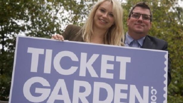 Eine Frau und ein Mann halten ein Schild mit der Aufschrift „Ticket Garden“.