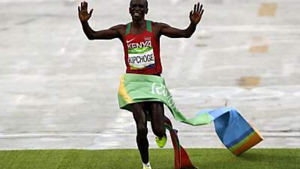 Eliud Kipchoge überquert die Ziellinie bei einem Marathon mit einer kenianischen Flagge um die Hüften.