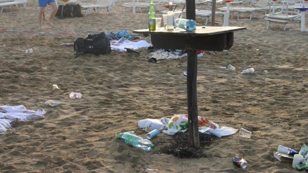 Ein verschmutzter Strand mit Müll und zurückgelassenen Gegenständen.