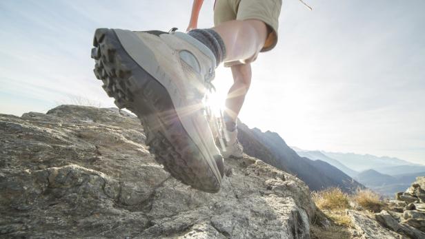 Wanderschuhe in Großaufnahme steigen über einen felsigen Pfad.