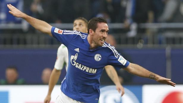 Ein Fußballspieler im blauen Trikot von Schalke 04 jubelt mit ausgestreckten Armen.