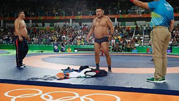 Ein Ringrichter zeigt einem mongolischen Ringer eine rote Karte bei einem Wettkampf.