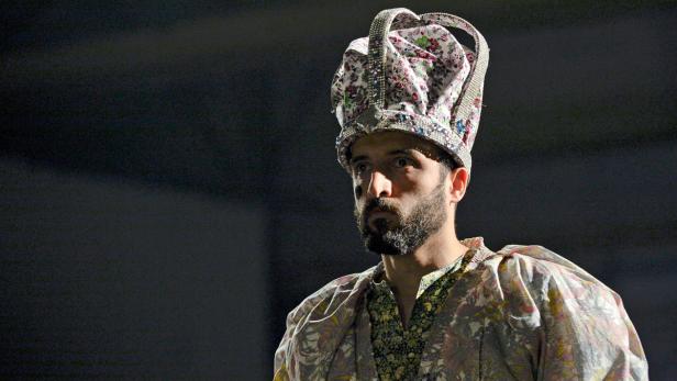 Ein Mann mit Bart und Krone blickt aufmerksam zur Seite.