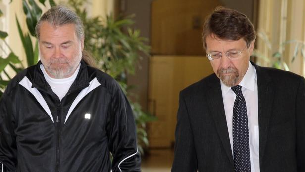 Zwei Männer stehen nebeneinander, einer in Trainingsjacke, der andere im Anzug.