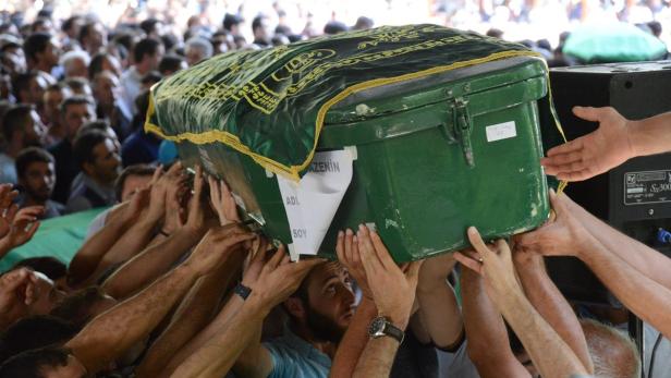 Eine Menschenmenge trägt einen grünen Sarg mit einer verzierten Decke.