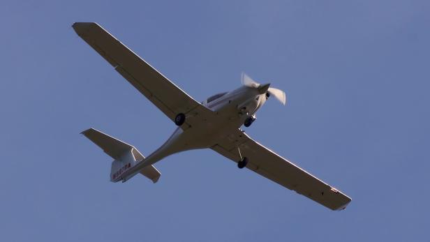 Ein kleines, weißes Flugzeug fliegt vor blauem Himmel.