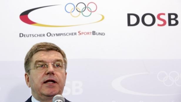 Thomas Bach, Präsident des Internationalen Olympischen Komitees, spricht vor einem DOSB-Logo.