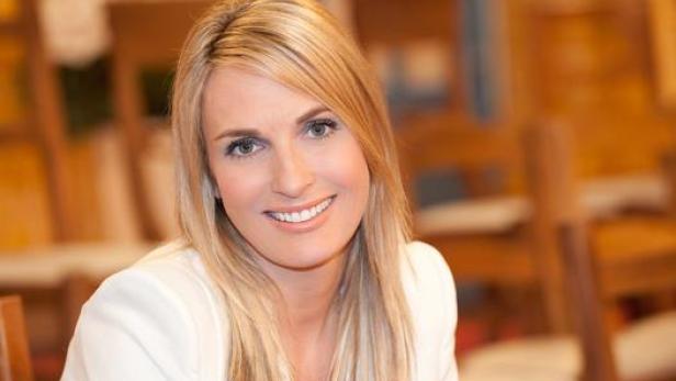 Eine Frau mit blonden Haaren lächelt in die Kamera.