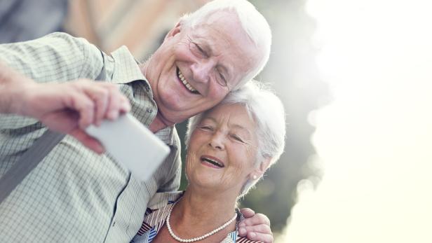 Ein älteres Paar macht ein Selfie und lacht.