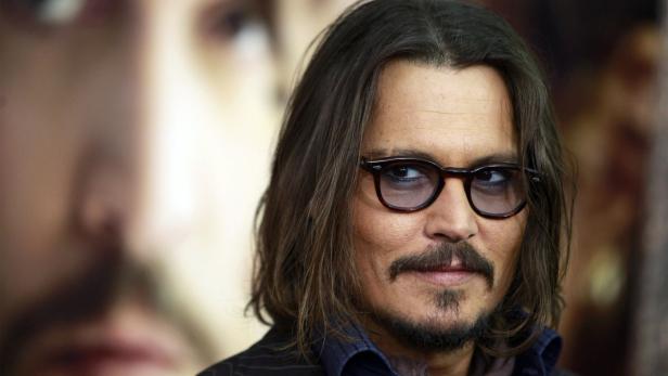 Porträt von Johnny Depp mit Brille und Bart vor einem unscharfen Hintergrund.