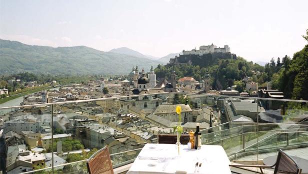 Blick von einer Terrasse auf Salzburg mit der Festung Hohensalzburg im Hintergrund.
