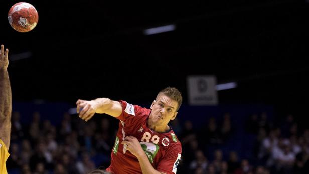 Ein Handballspieler im roten Trikot wirft einen Ball.