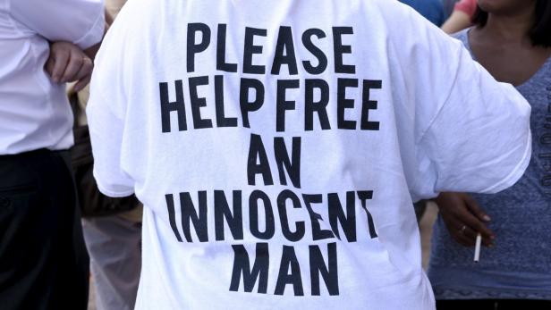 Eine Person trägt ein T-Shirt mit der Aufschrift „Please help free an innocent man“.