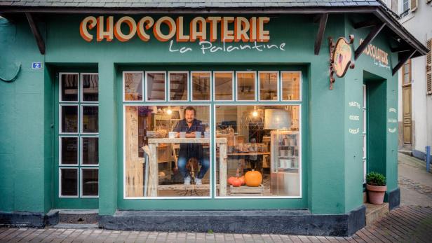 Ein Mann sitzt in der Auslage der „Chocolaterie La Palantine“.