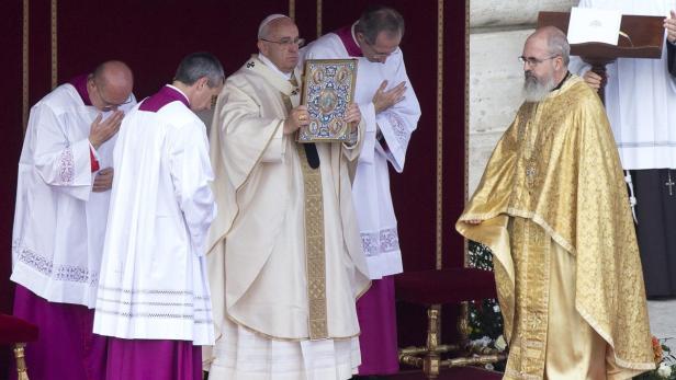 Papst Franziskus hält ein reich verziertes Buch während einer Zeremonie.