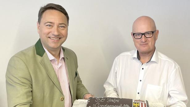 Manfred Haimbucher überreicht Hubert Schreiner eine Torte zum 30. Dienstjubiläum