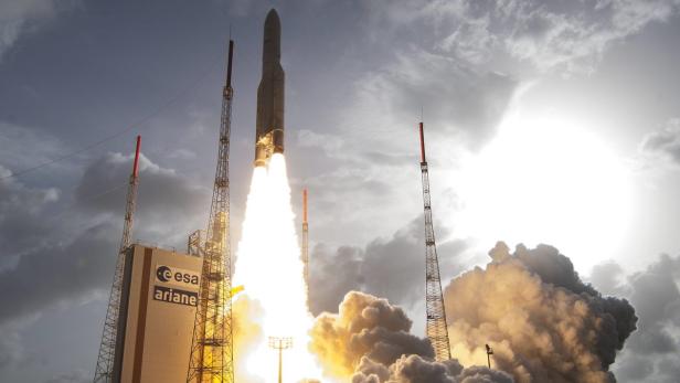 Eine Ariane-Rakete startet mit hellem Feuer und Rauch von einer Startrampe.