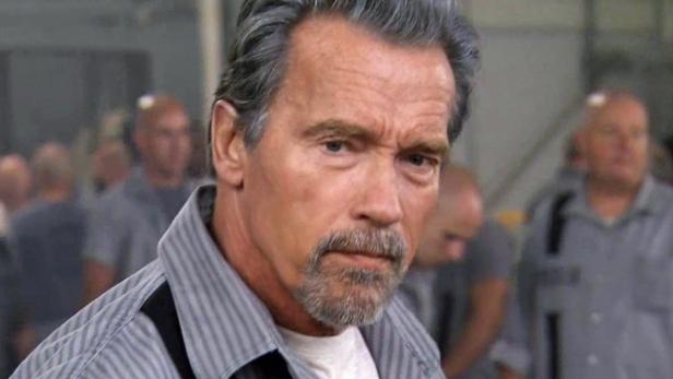 Arnold Schwarzenegger in gestreifter Gefängnisuniform.