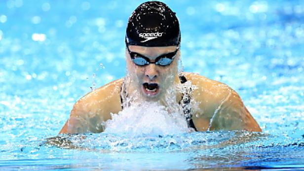Eine Schwimmerin mit Schwimmbrille und Badekappe beim Brustschwimmen.