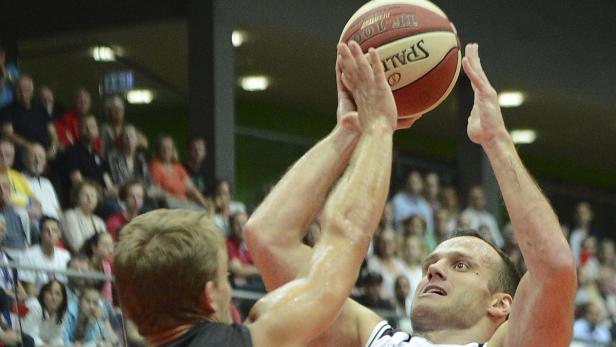 Ein Basketballspieler springt, um einen Spalding-Basketball zu fangen.