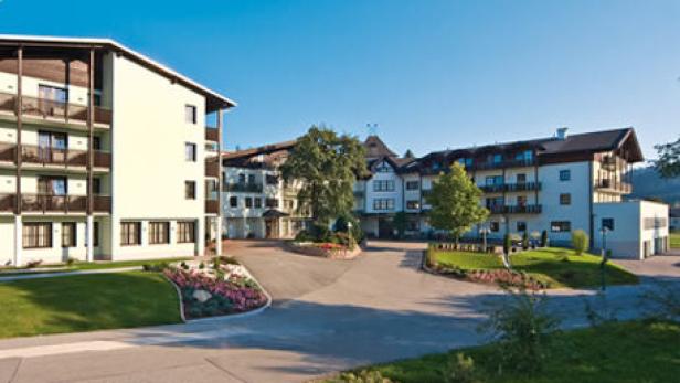 Ein großes Hotelgebäude mit gepflegten Grünflächen und Blumenbeeten im Außenbereich.